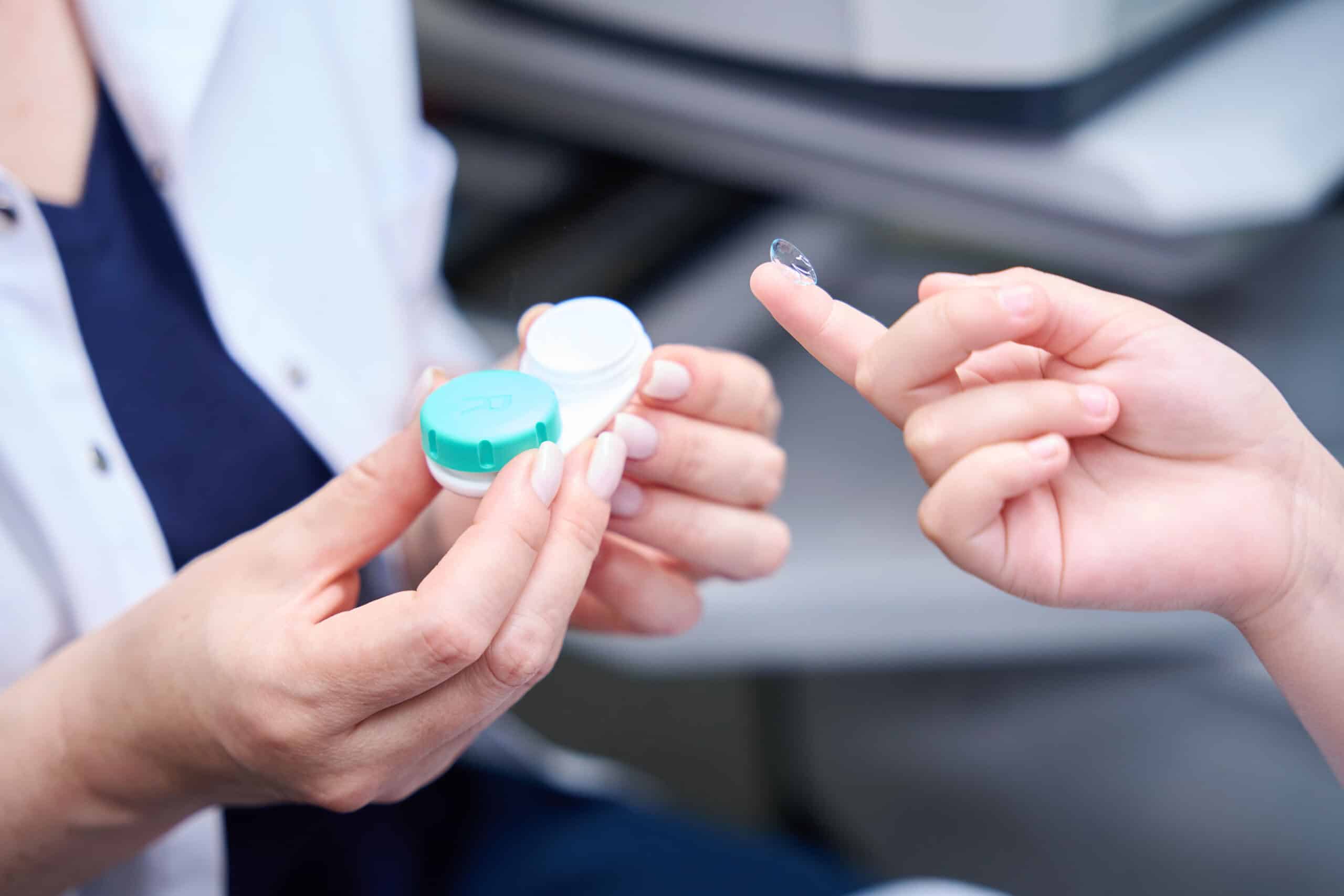 Cropped photo of child hand holding contact lens on fingertip in front of oculist